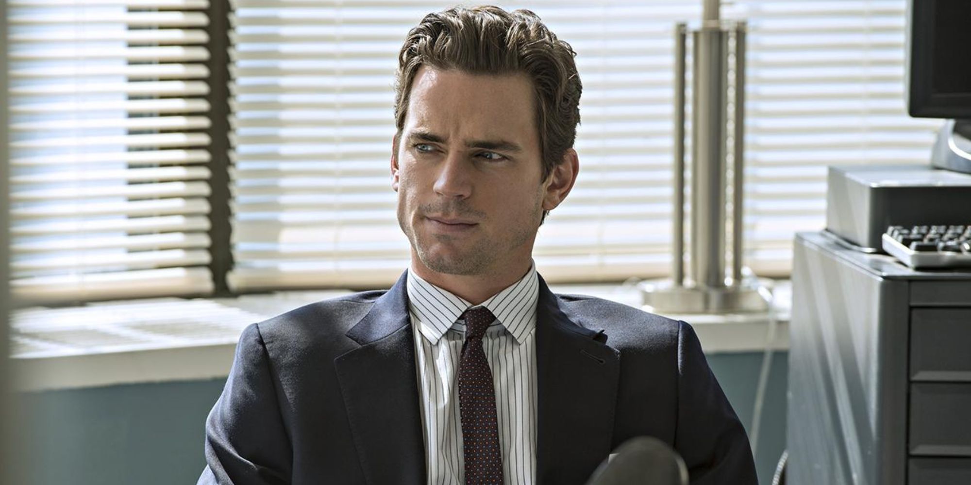 Matt Bomer as Neil Caffrey sitting in an office in White Collar