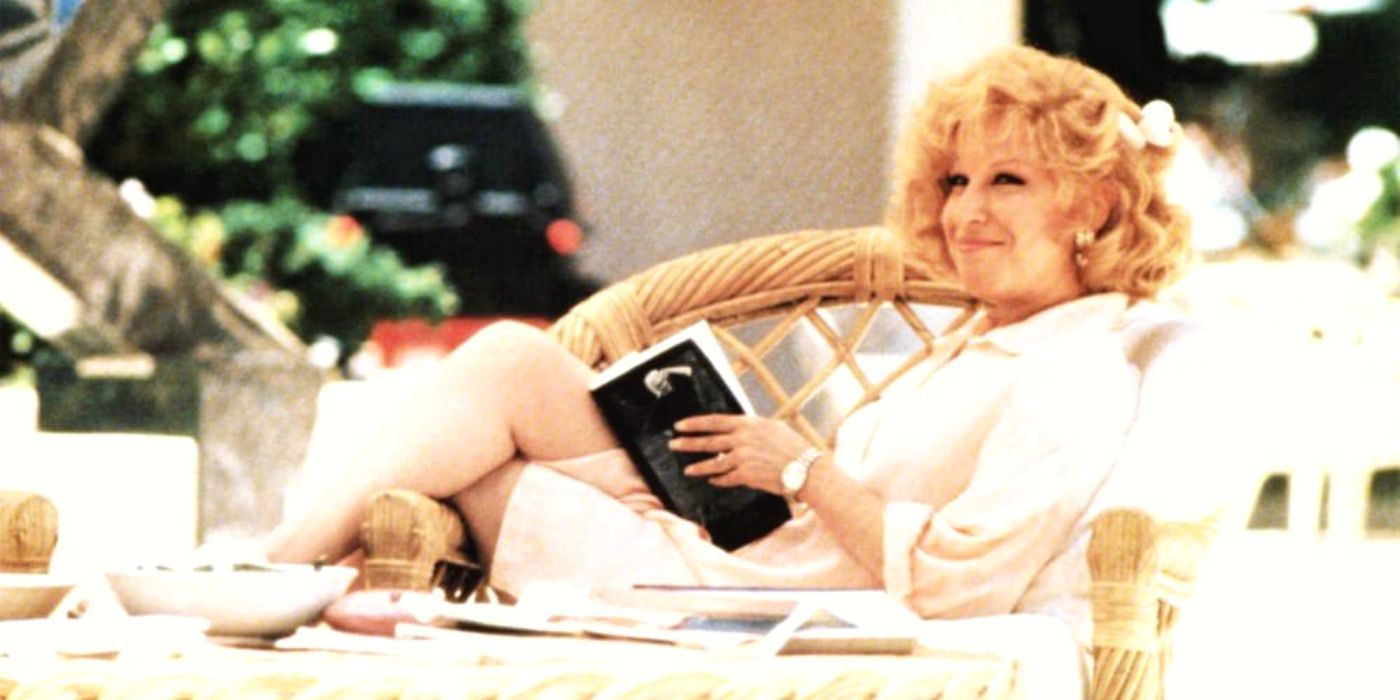 Bette Midler sitting on a couch with a book in Down and Out in Beverly Hills (1986)