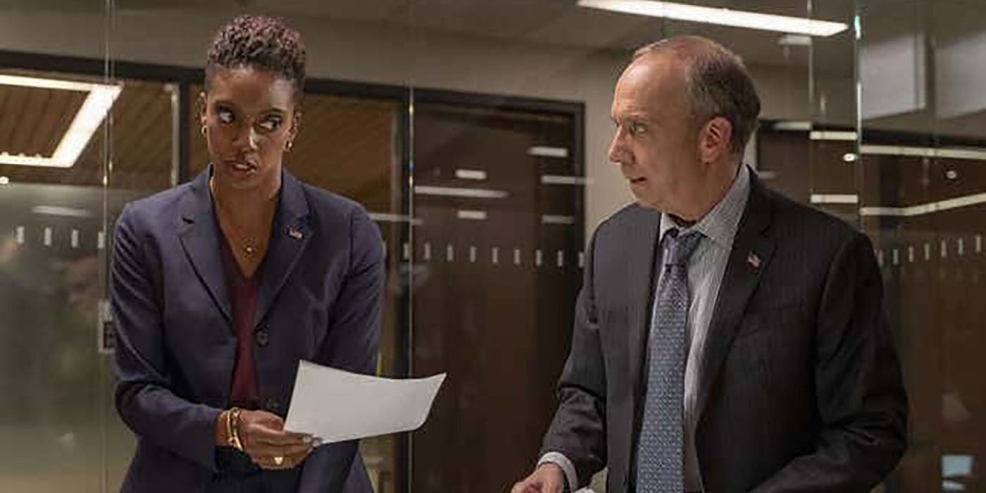 Kate handing a piece of paper to Chuck, looking annoyed in a scene from Billions.