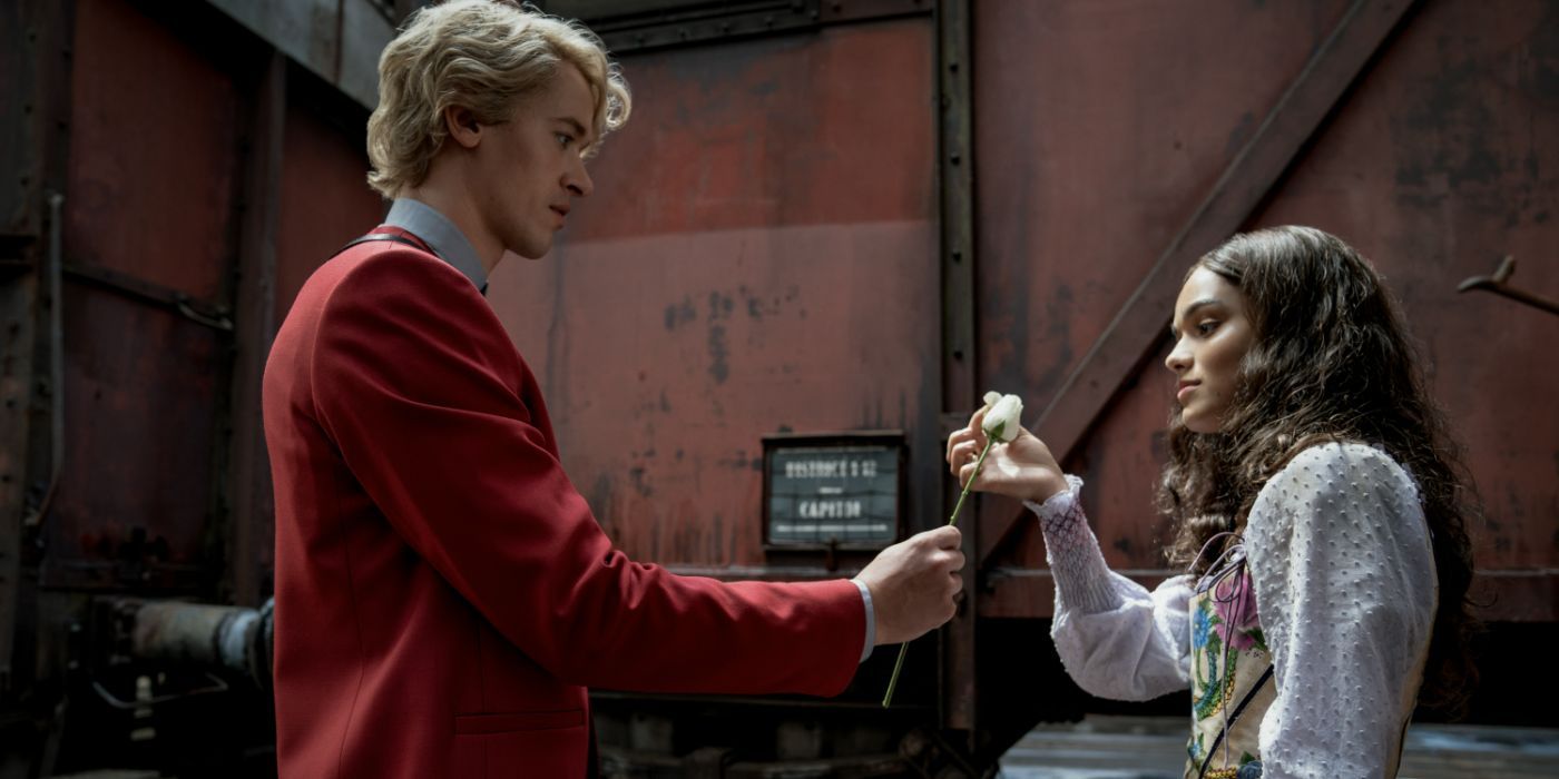 Coriolanus Snow (Tom Blythe) hands Lucy Gray Baird (Rachel Zegler) a white rose