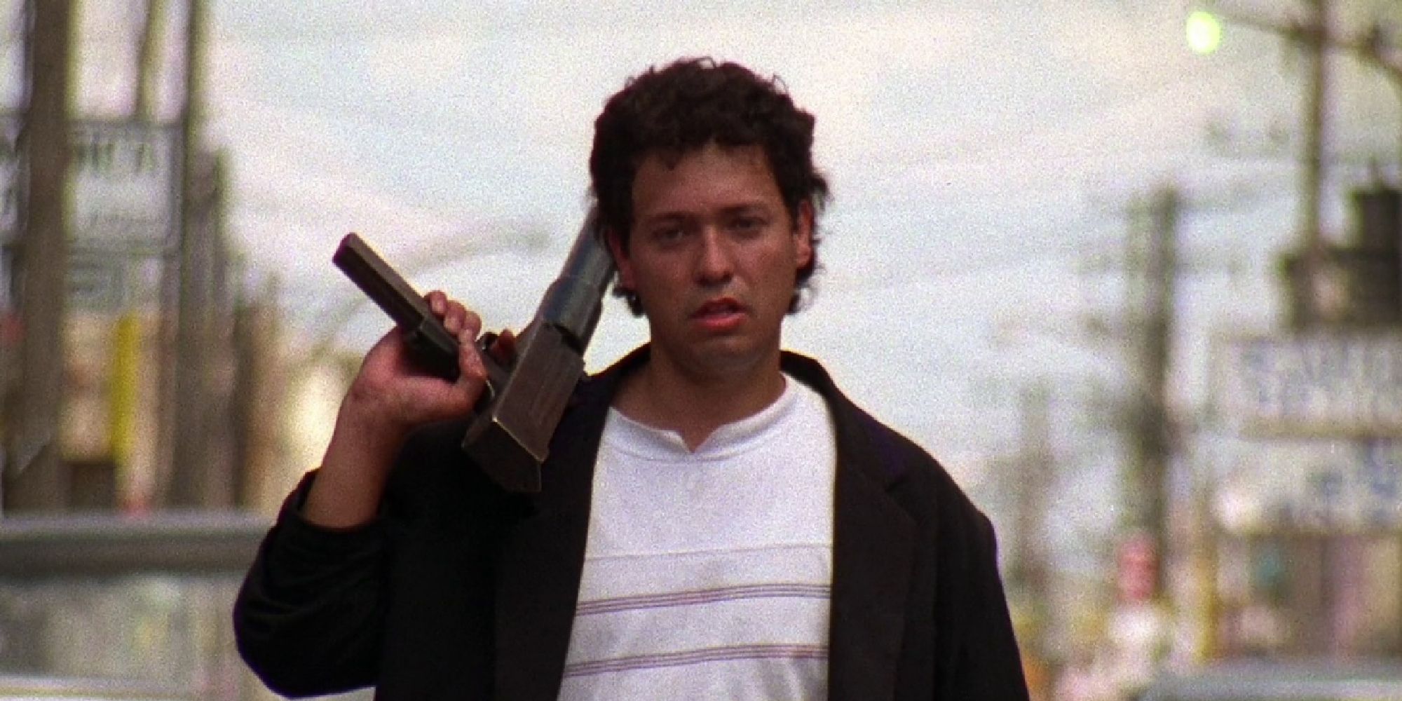 El Mariachi holding a gun over his shoulder while walking in El Mariachi