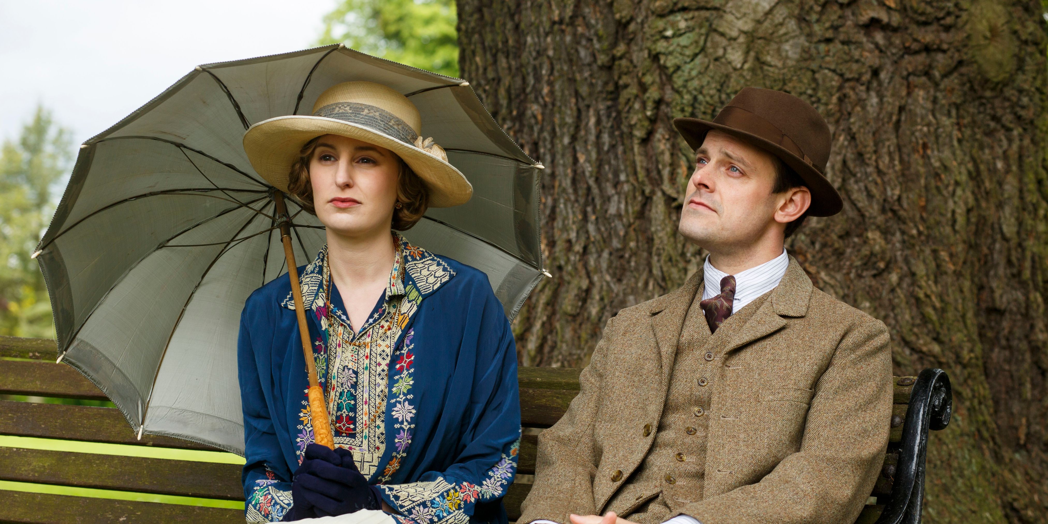 Edith (Laura Carmichael) and Bertie Pelham (Harry Hadden-Paton) sitting on a bench while Edith holds an umbrella in 'Downton Abbey'