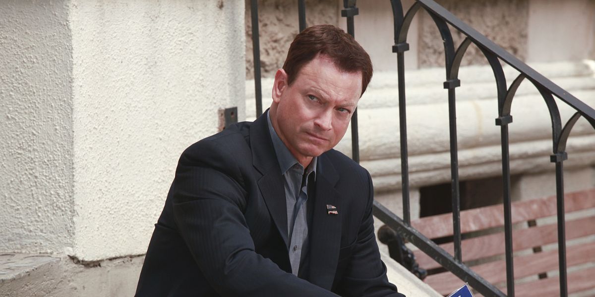 Gary Sinise sitting on stairs in a suit.