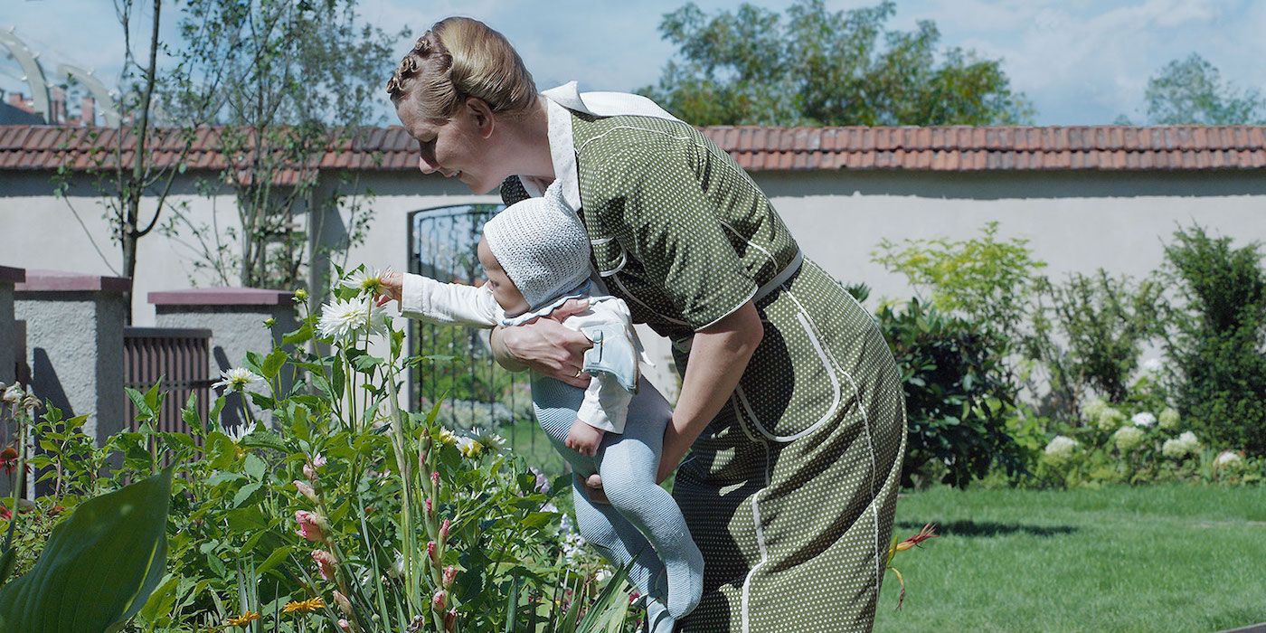 Sandra Hüller as Hedwig Höss picks flowers in her garden with her baby in The Zone of Interest