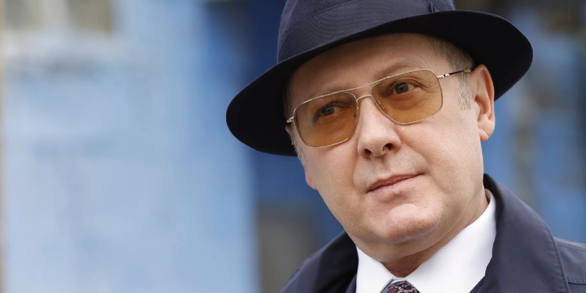 James Spader in The Blacklist wearing a top hat, head cocked.