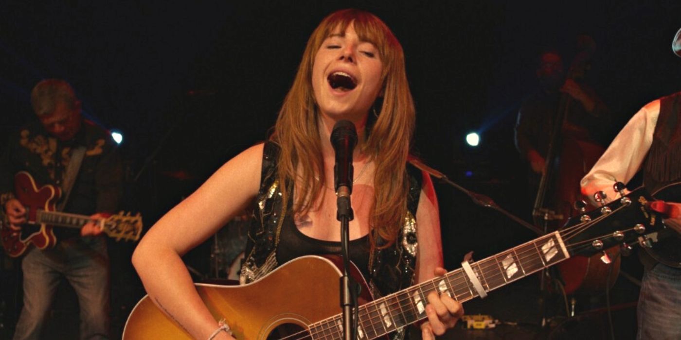 Jessie Buckley singing and playing guitar on stage in Wild Rose (2018)