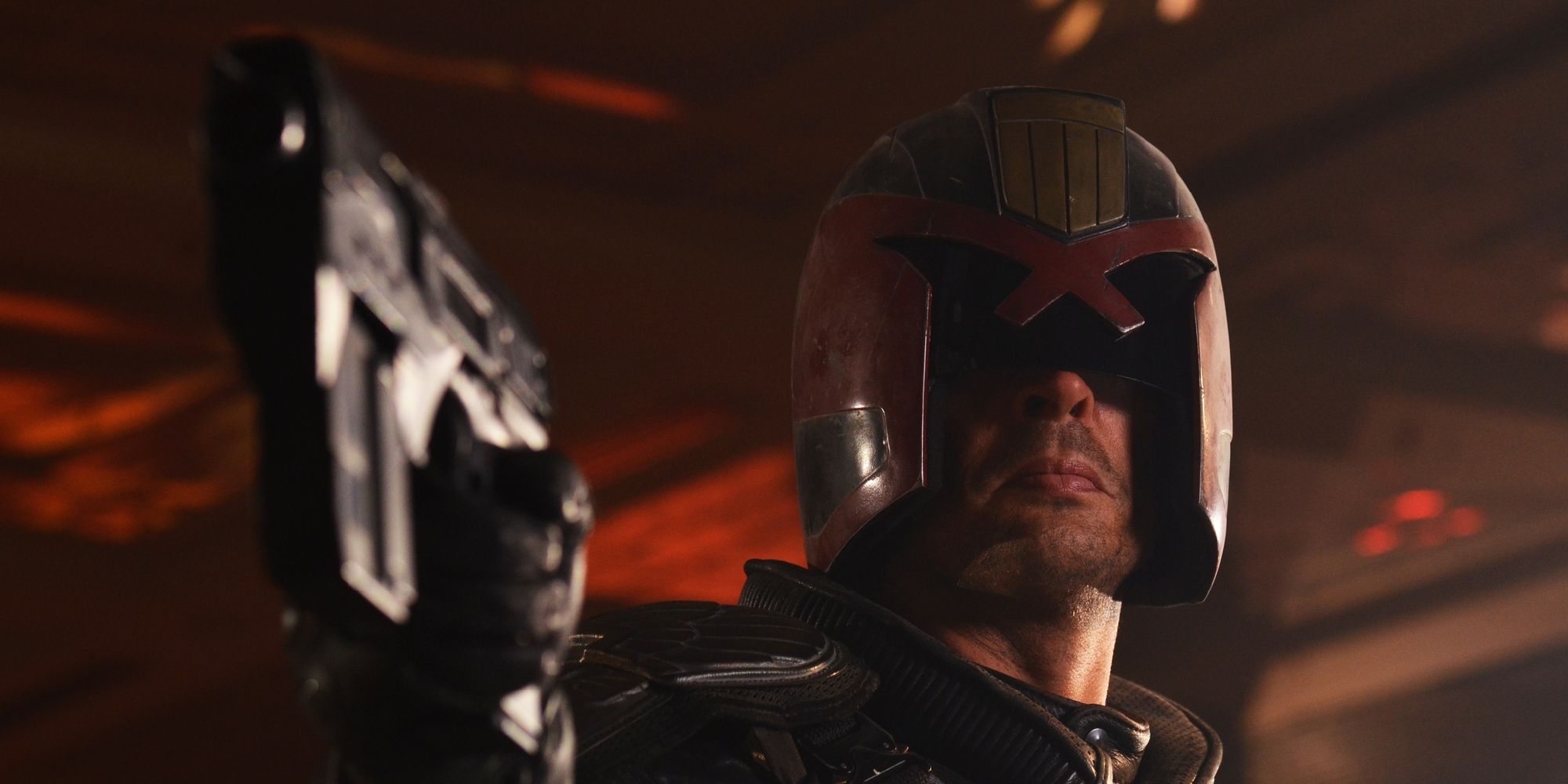 Karl Urban en Judge Dredd apunta con un arma a alguien.