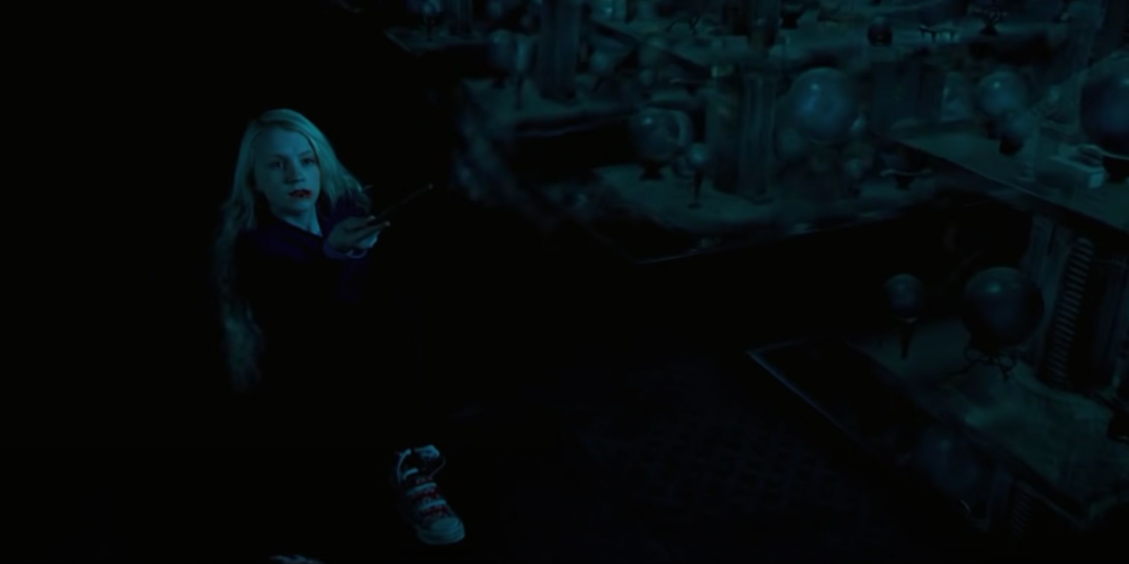 Lying back on the ground with a bloodied mouth, Luna Lovegood defends herself by casting Levicorpis on a Death Eater in the Prophecy Room.