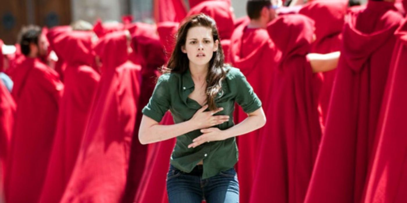 Bella (Kristen Stewart) with her hands on her chest, looking concerned, as she stands amongst a group of red-hooded Volturi in Twilight: New Moon