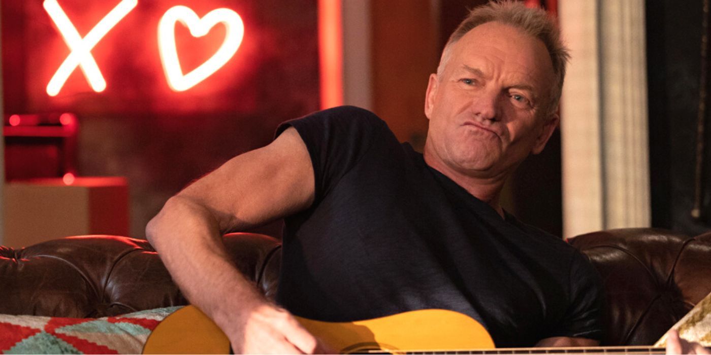 Sting sitting on a couch and playing guitar in Only Murders in the Building