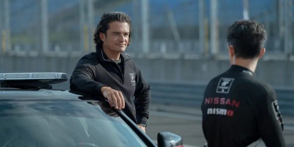 Orlando Bloom as Danny Moore in Gran Turismo, leaning on a car.