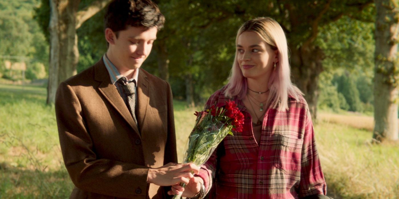Maeve (Emma Mackey) looking over and smiling at Otis (Asa Butterfield), who is holding a small bouquet of flowers in Sex Education Season 1