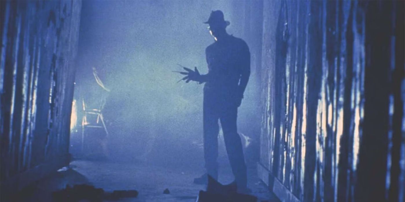 Freddy Krueger (Robert Englund) standing in a dark alley with his gloved knifed hand extended out in Nightmare on Elm Street