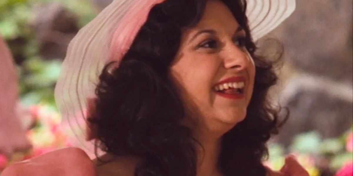 Jeannie Linero as Lucy Mancini, wearing a pink hat and dress and smiling in The Godfather