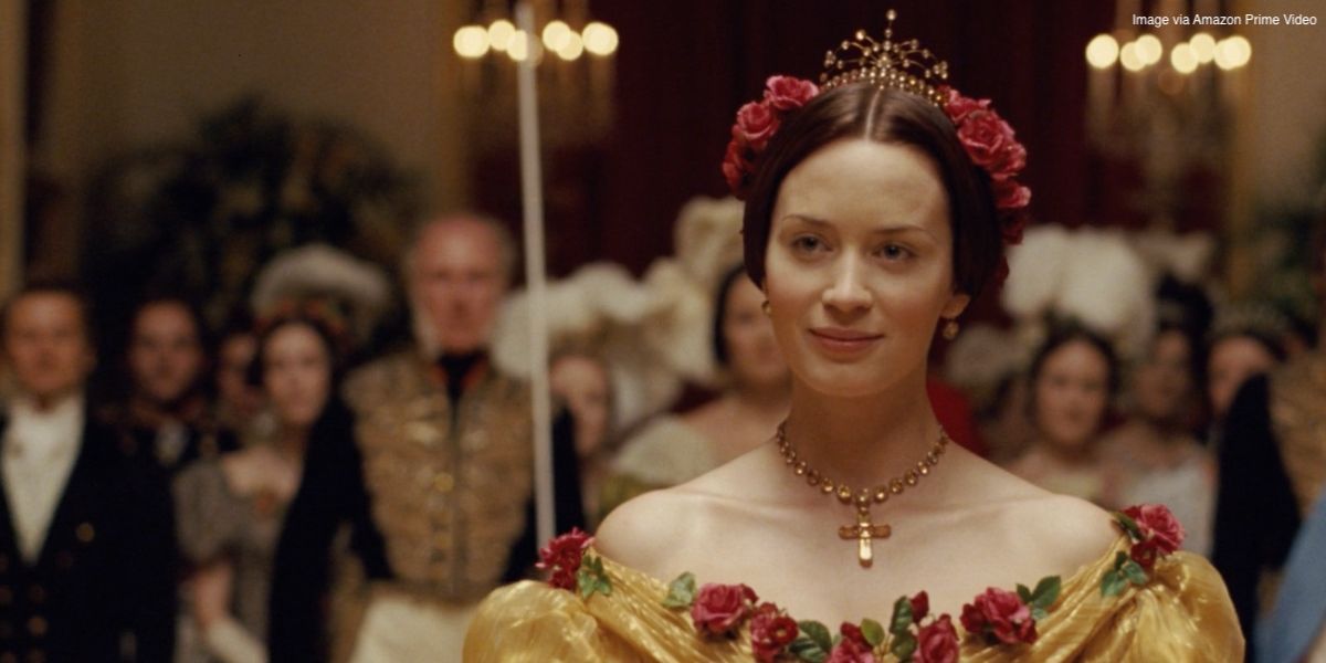 Emily Blunt smiling while wearing a yellow ballgown and pink roses in her hair in 'The Young Victoria'