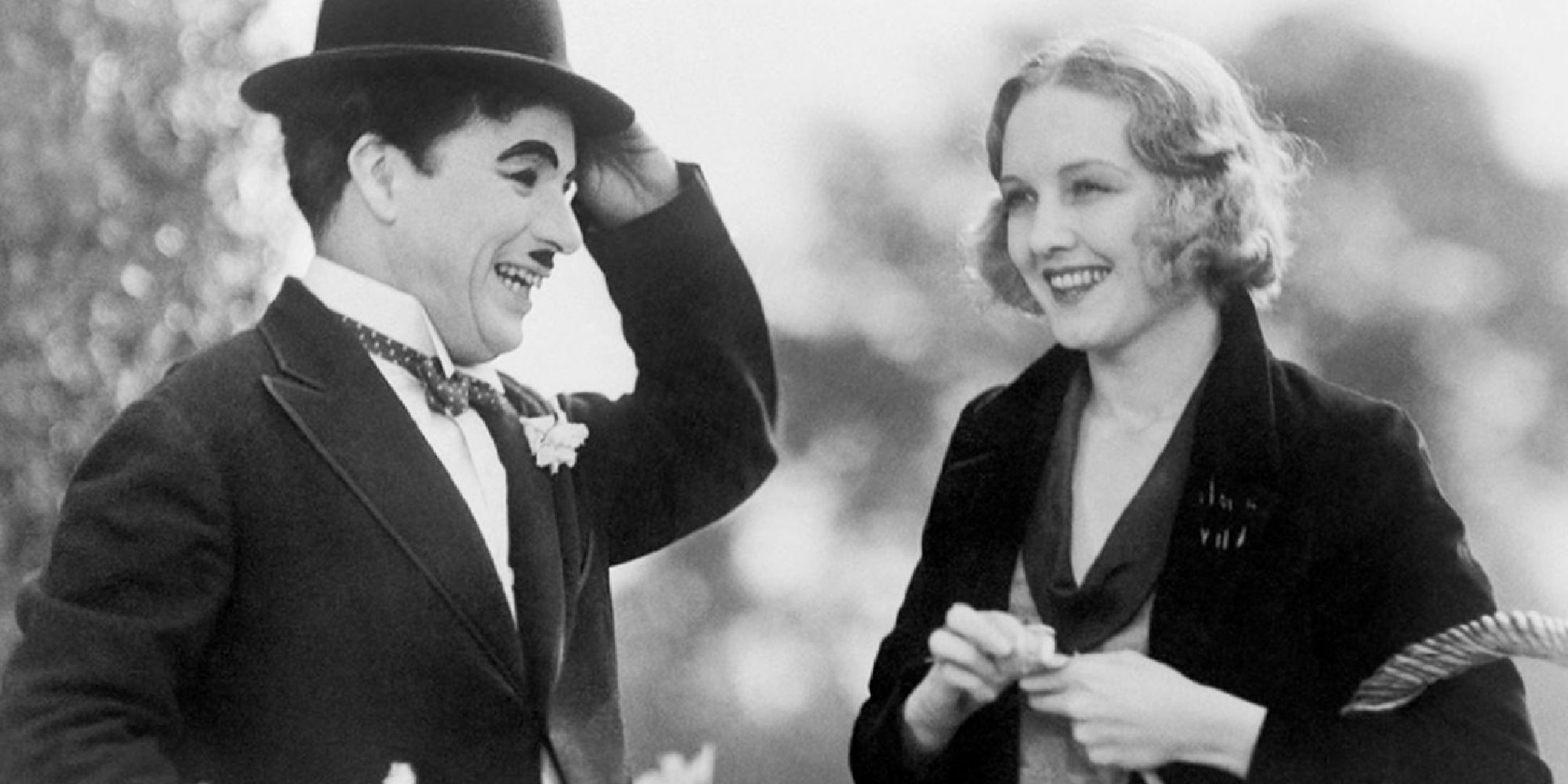 Charlie Chaplin and Virginia Cherrill smiling while standing next to each other in City Lights.