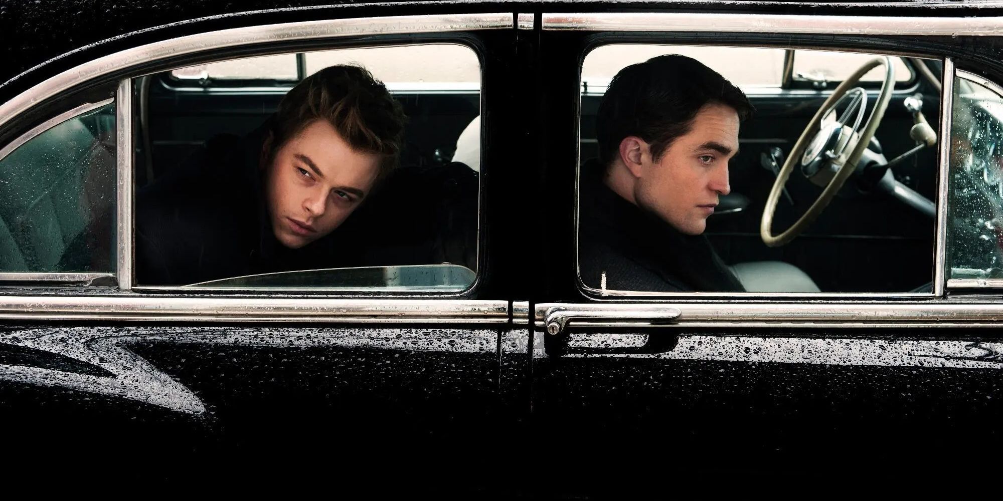 Dane Dehaan and Robert Pattinson as James Dean and Dennis Stock inside a car lookint at the camera in Life