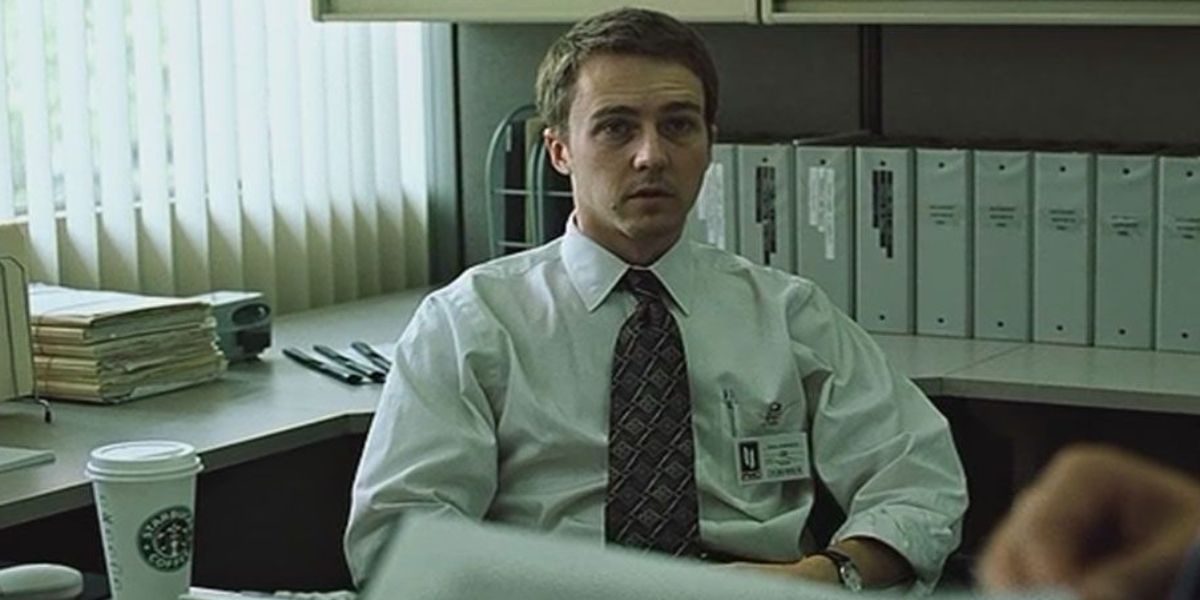 Edward Norton as the Narrator sitting at his desk in Fight Club 
