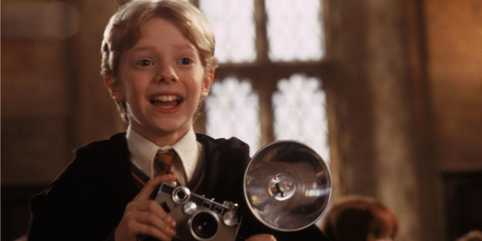 Colin Creevey (Hugh Mitchell) smiles and holds camera in Harry Potter and the Chamber of Secrets