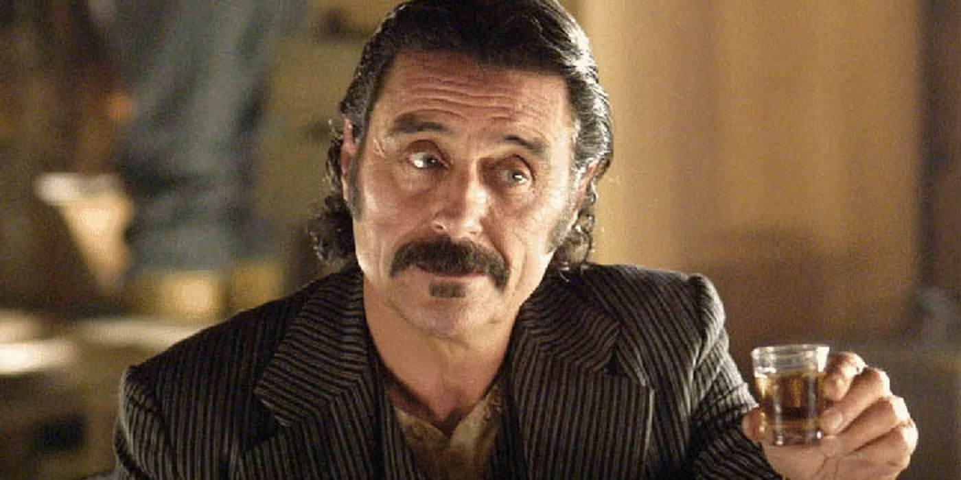 Ian McShane as Al Swearengen holding up a shot of liquor in 'Deadwood.' 