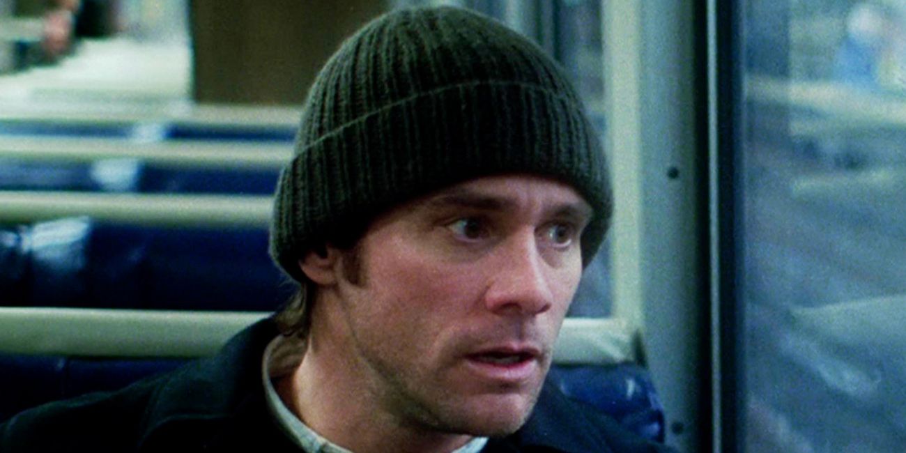 A young man in a beanie looks out a bus window with a devastated look on his face.