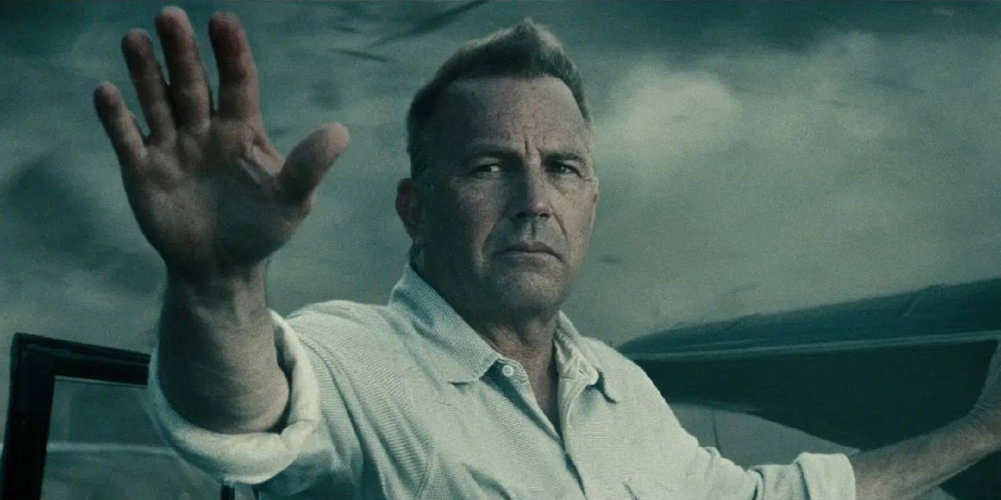 Kevin Costner as Jonathan Kent, holding his arms outstretched and looked somber in Man of Steel