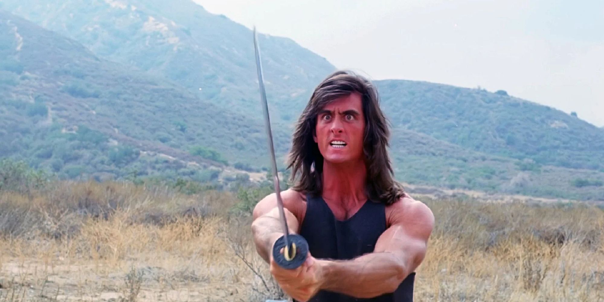 Matt Hannon stands in a desert holding a sword in Samurai Cop