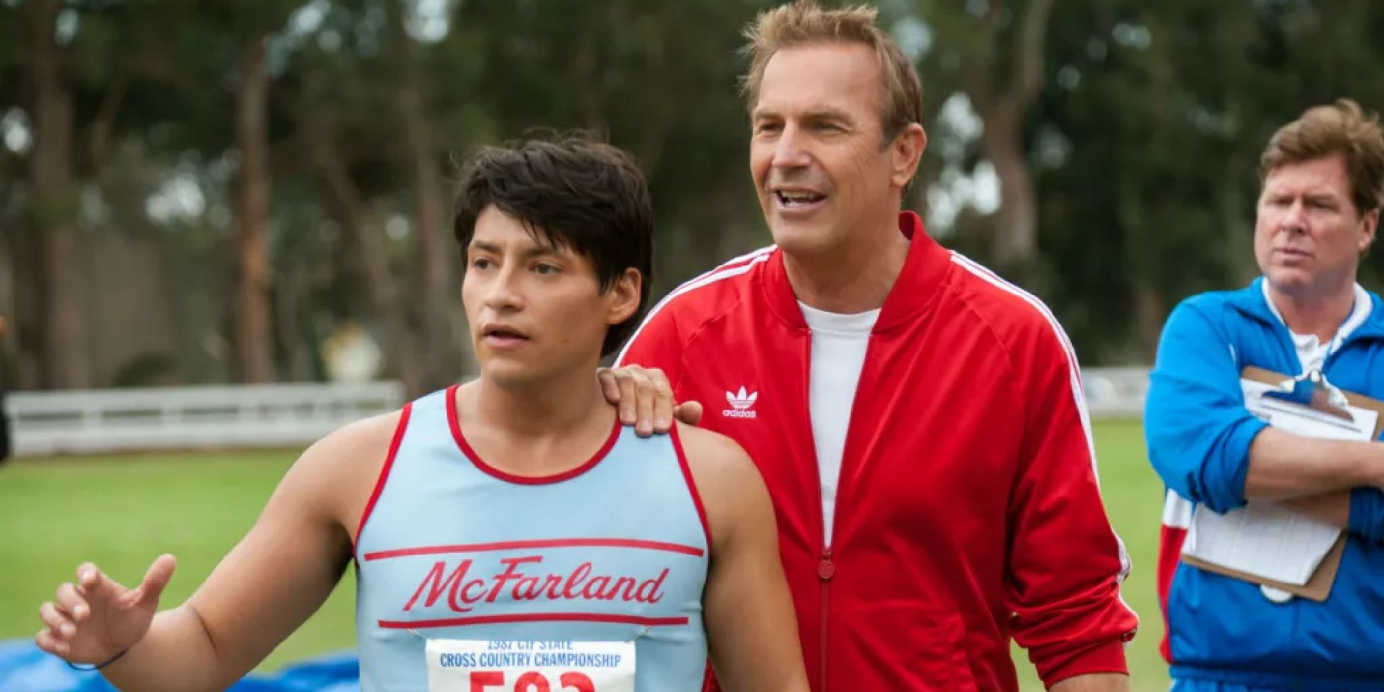 Kevin Costner as Jim White with his hand on a young man's shoulder in McFarland, USA