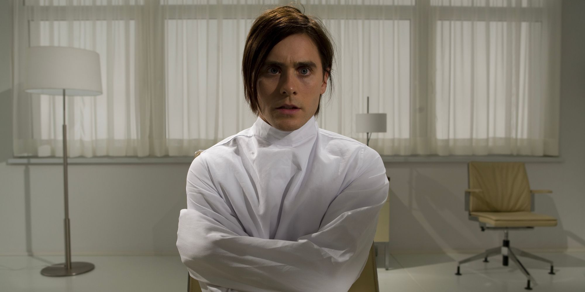 A young man, Nemo Nobody, sits in a straight jacket in a sterile, white room.