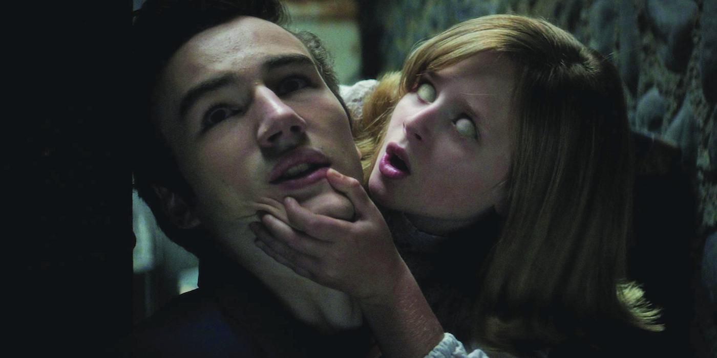 A possessed young girl holding a guy by the jaw in Ouija Origin of Evil