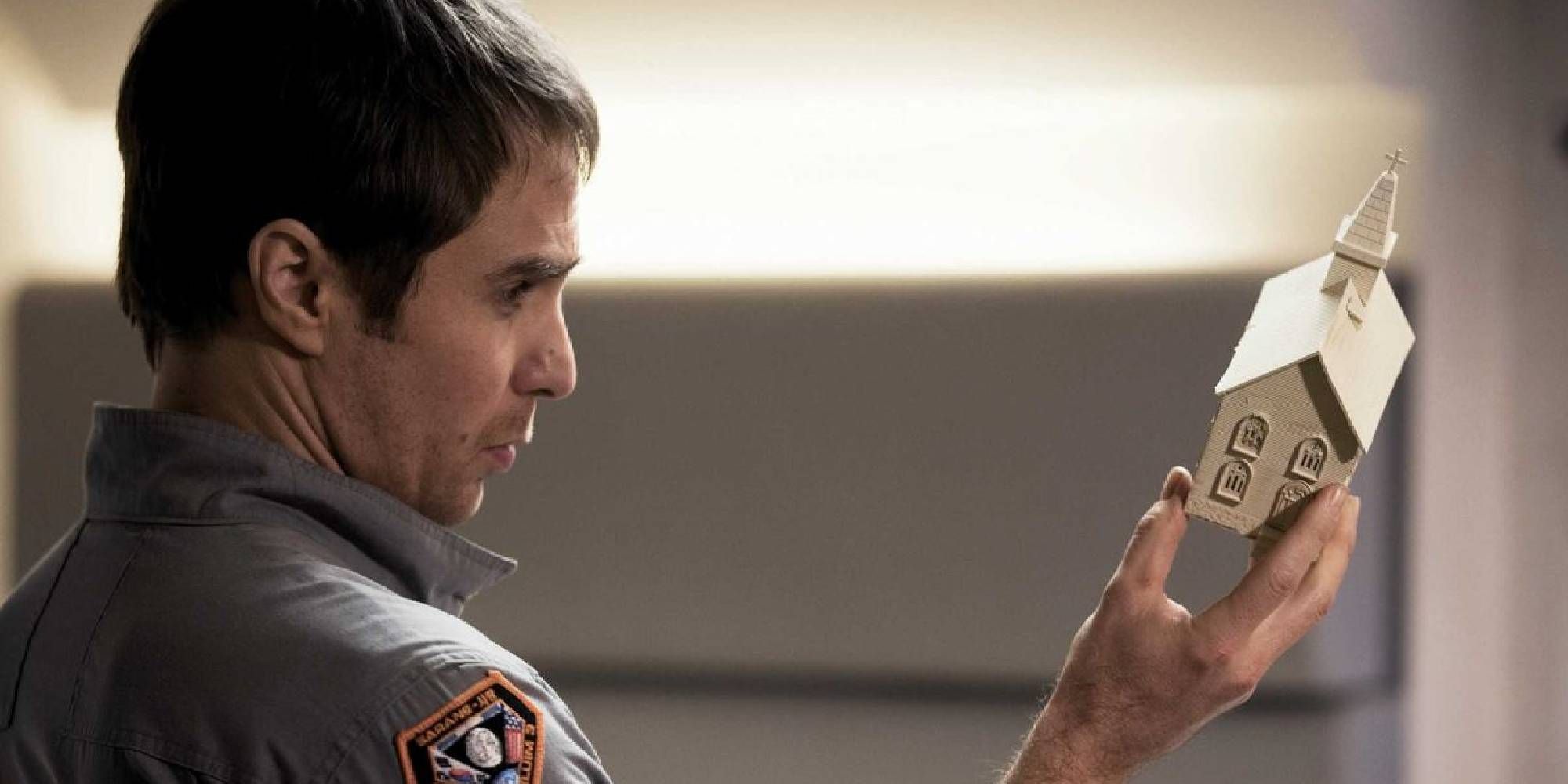 Sam Rockwell's character Sam Bell holding a little house in Moon.