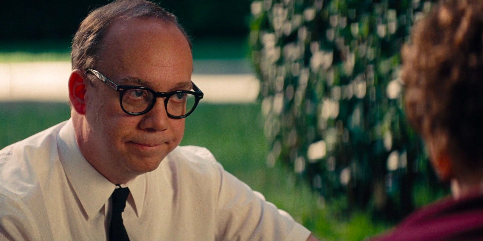 Ralph (Paul Giamatti), a chauffeur for P. L. Travers (Emma Thompson) sits on the grass with the author having a conversation.