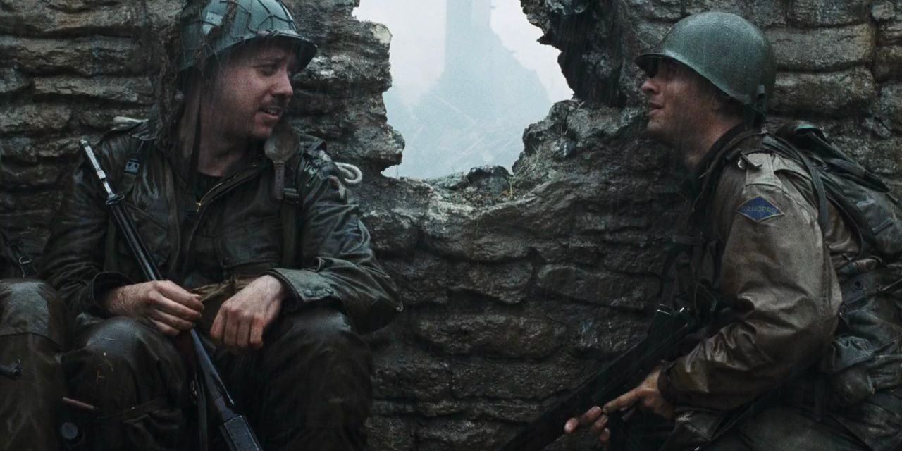 Two U.S. soldiers take cover behind a bombarded brick wall in the rain in 'Saving Private Ryan'
