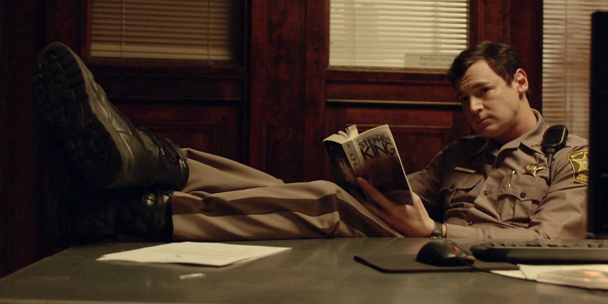 Zeke Sikes wearing a police uniform and reading a book in Shimmer Lake