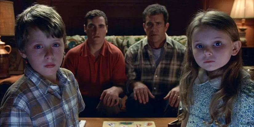 Morgan, Merril, Graham, and Bo Hess looking straight at the camera with serious expressions in Signs.