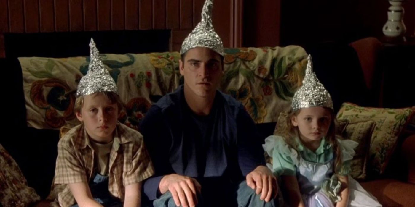 Joaquin Phoenix, Rory Culkin, and Abigail Breslin sitting together in tin foil hats in 'Signs'