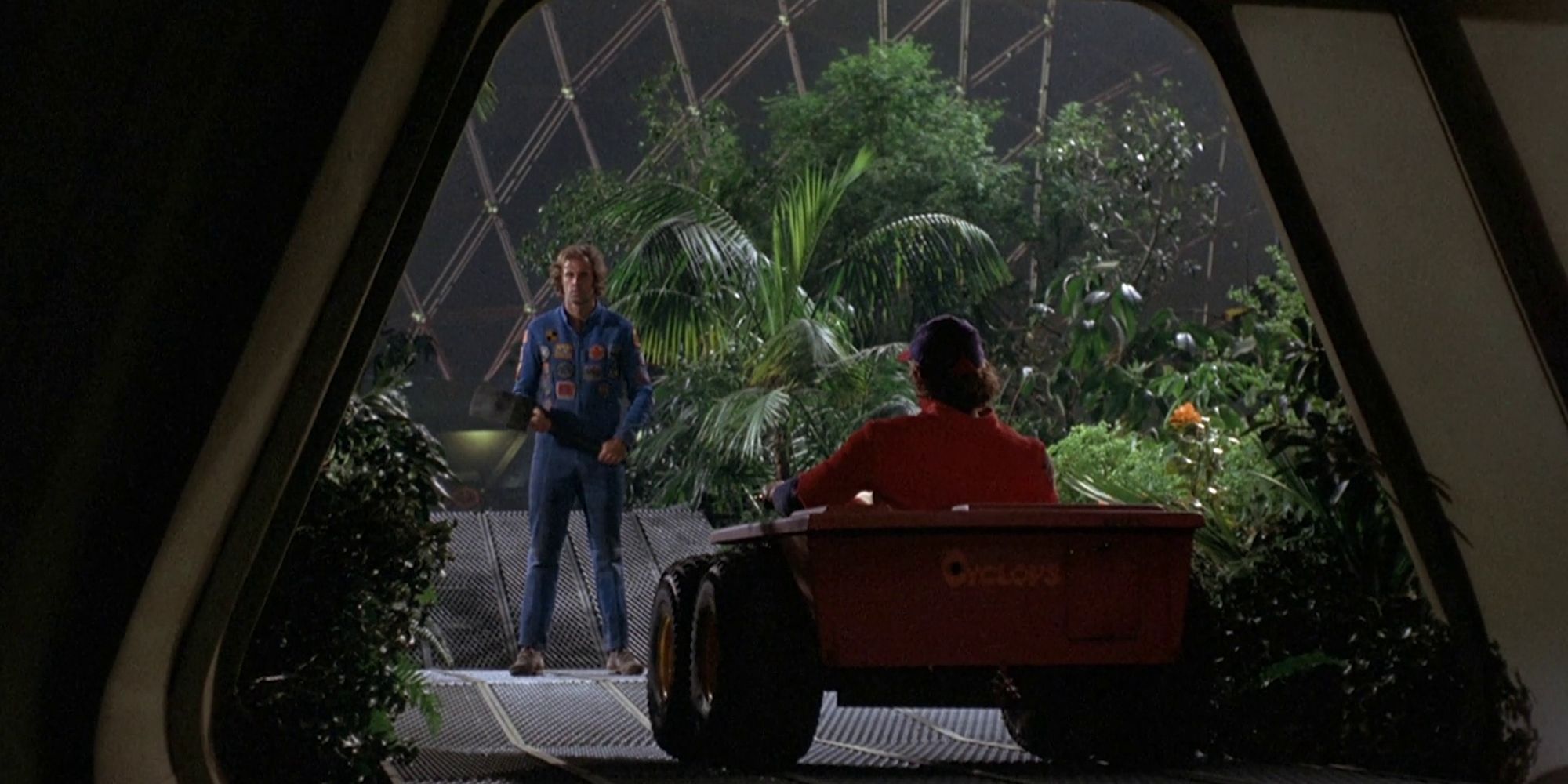 A man in a car approaches another man inside a greenhouse in the film Silent Running.