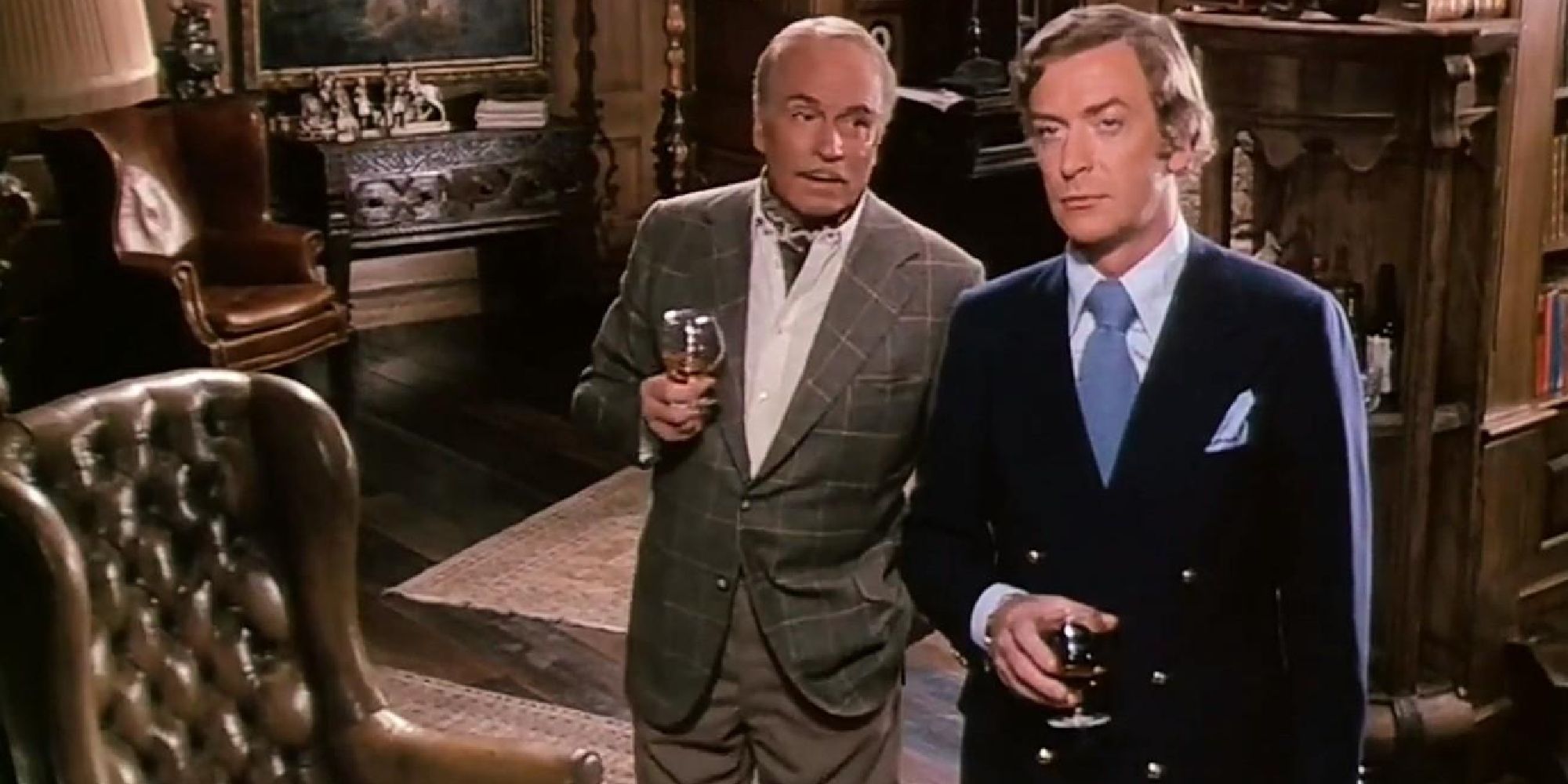 Michael Caine and Laurence Olivier standing together and sharing a drink in Sleuth (1972).