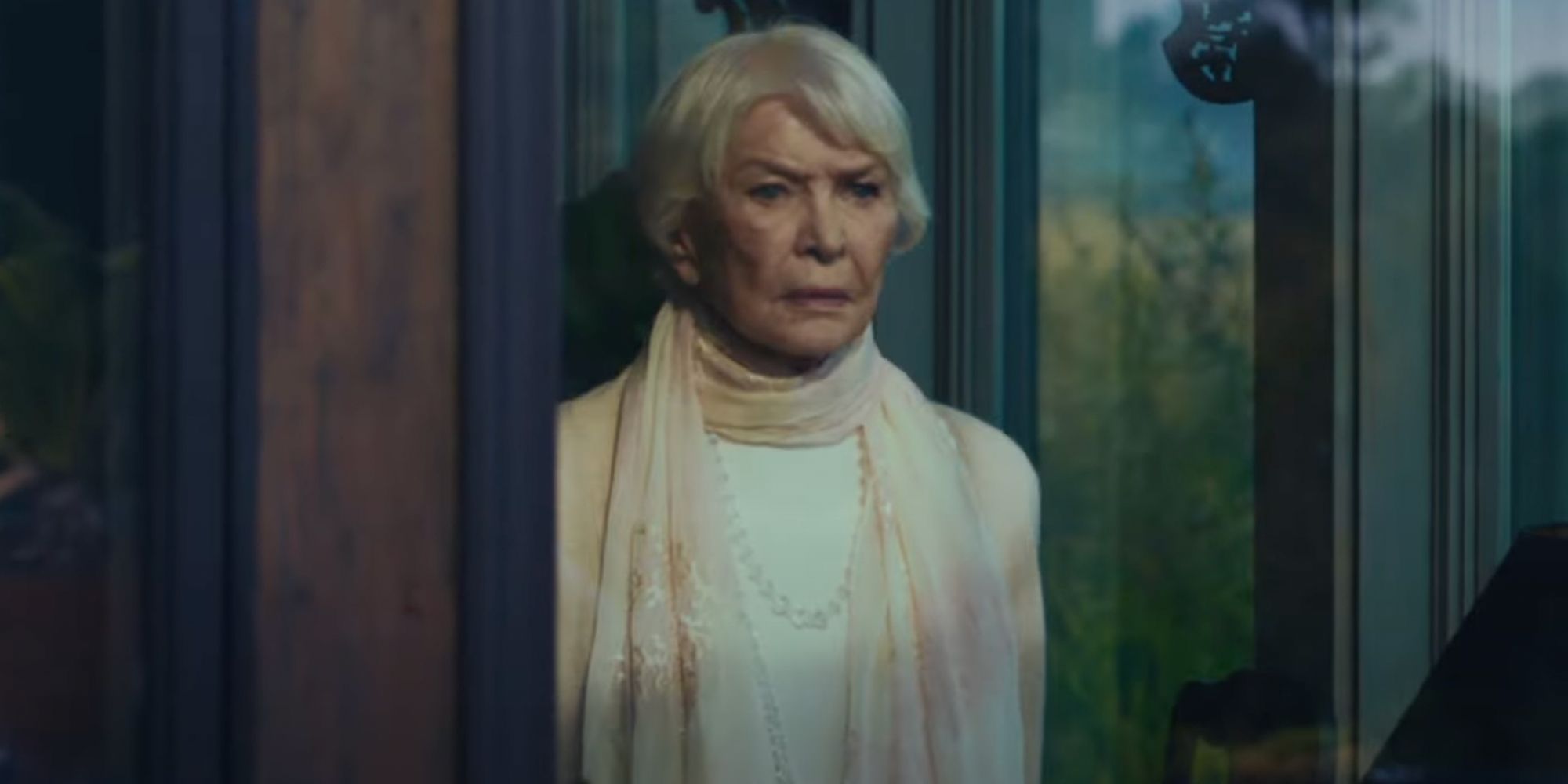 Chris McNeil (Ellen Burstyn) frunce el ceño y mira por la ventana en The Exorcist Believer.