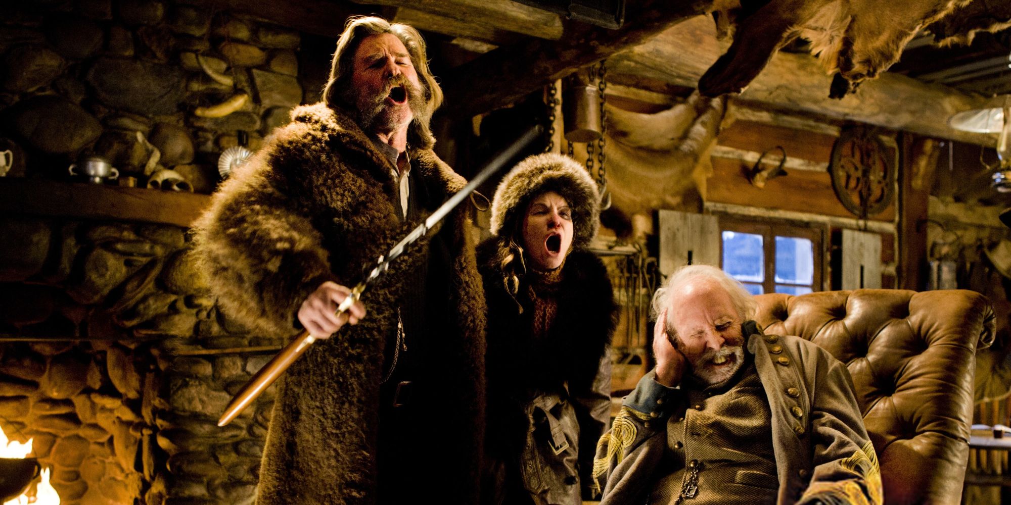 Kurt Russell as John Ruth holding a rifle next to Jennifer Jason Leigh as Daisy Domergue. Both are vocalizing loudly near Bruce Dern as Sheriff Randy Smithers in The Hateful Eight