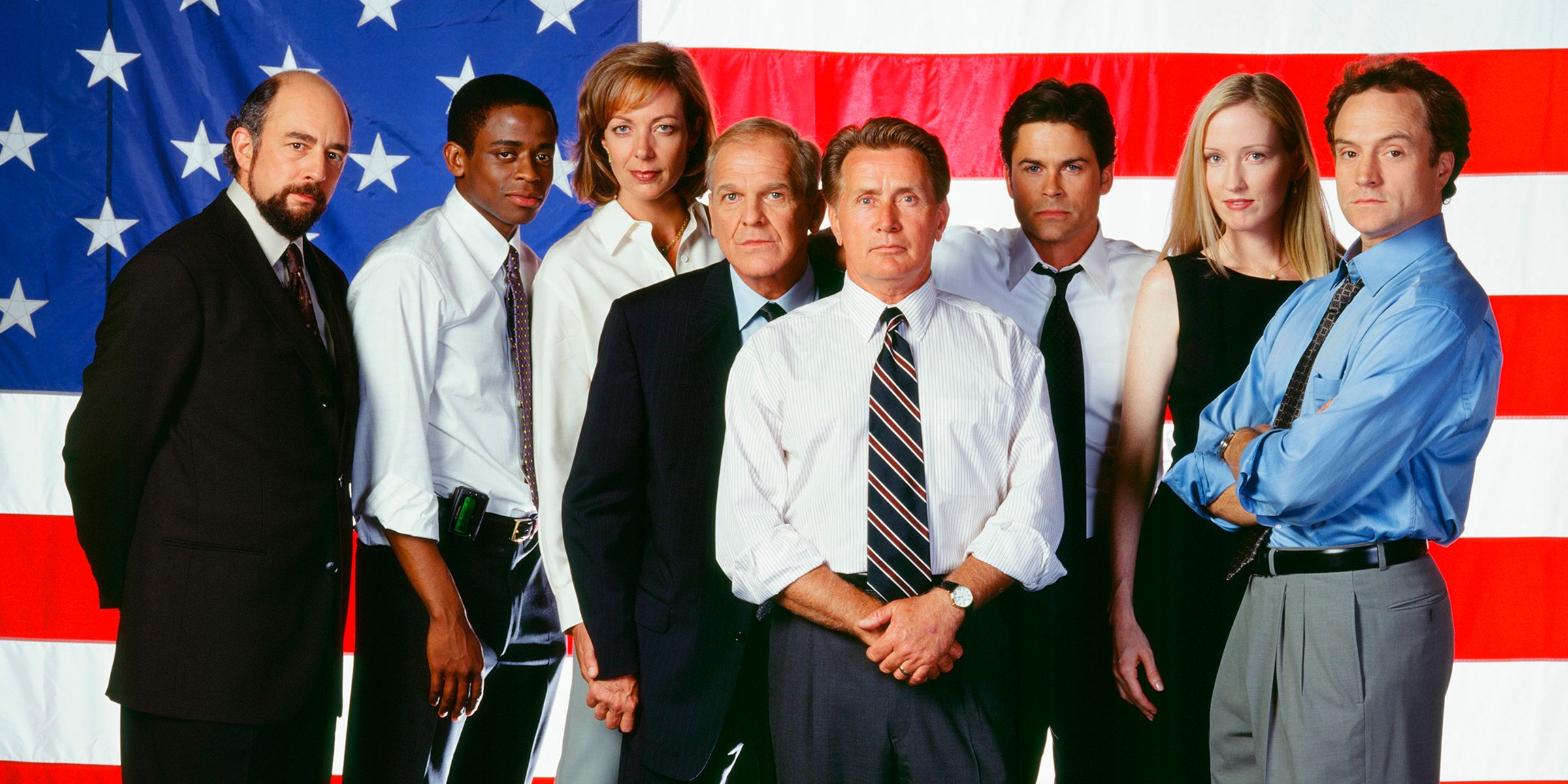 The West Wing Cast in front of an American flag.