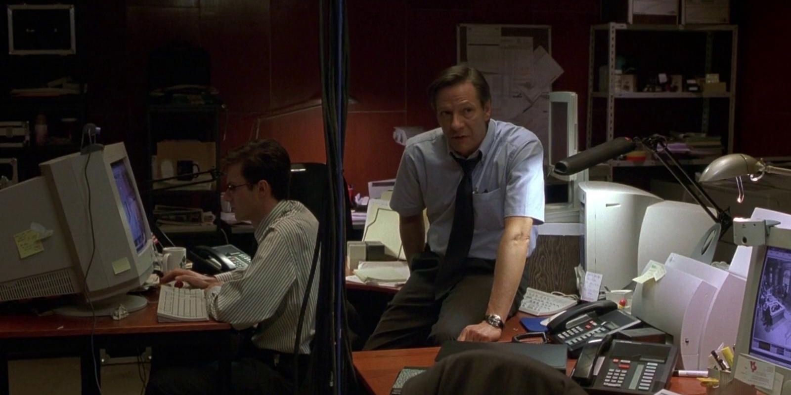 Chris Cooper as Alexander Conklin sitting in an office looking somewhere off-camera in The Bourne Identity