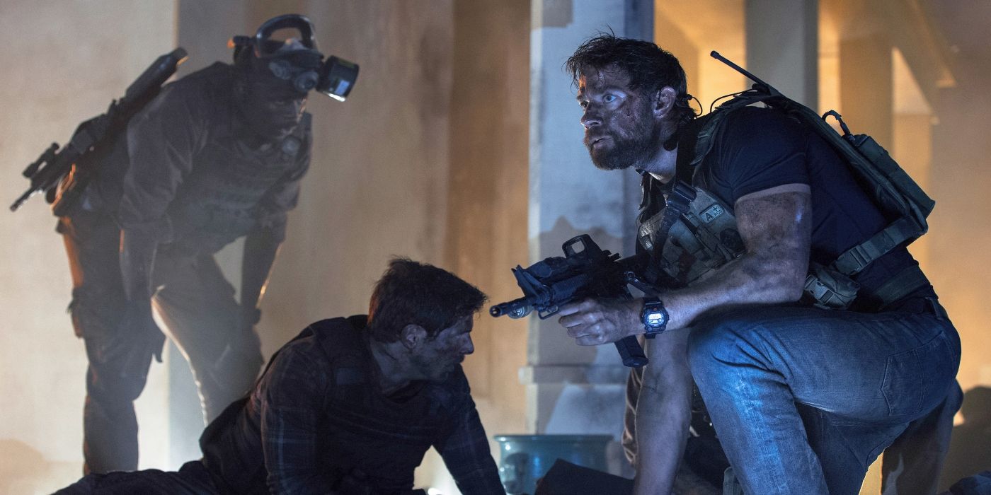 John Krasinski as Jack Silva keenling beside a falle soldier while looking ahead in 13 Hours: The Secret Soldiers of Benghazi.