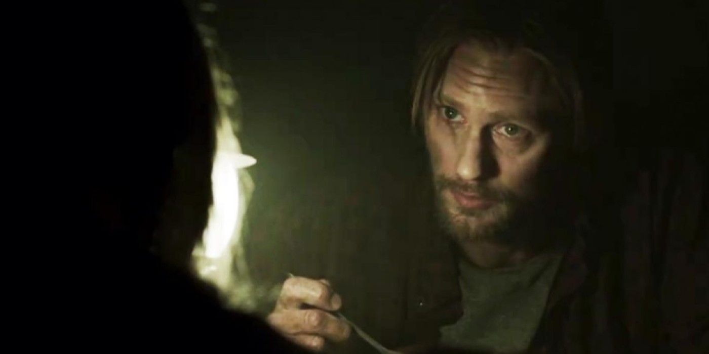 Alexander Skarsgard as Ray looking at someone off-camera in a dark room in the film Hidden