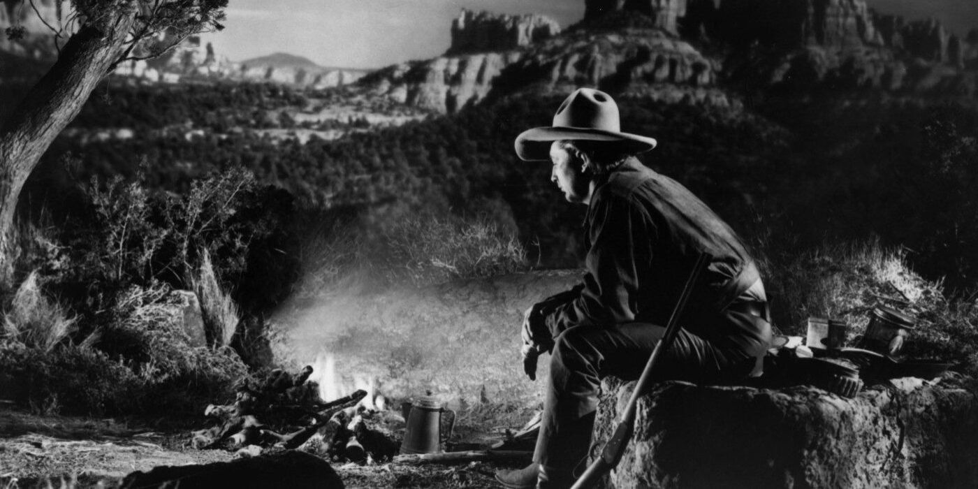 Robert Mitchum as Jim Garry sitting by a campfire in Blood on the Moon