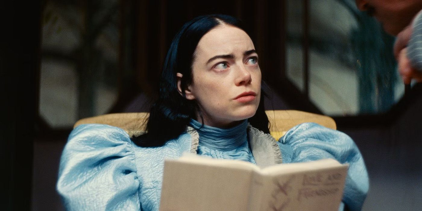 Emma Stone as Bella Baxter, holding a book and looking seriously at someone off-camera in Poor Things