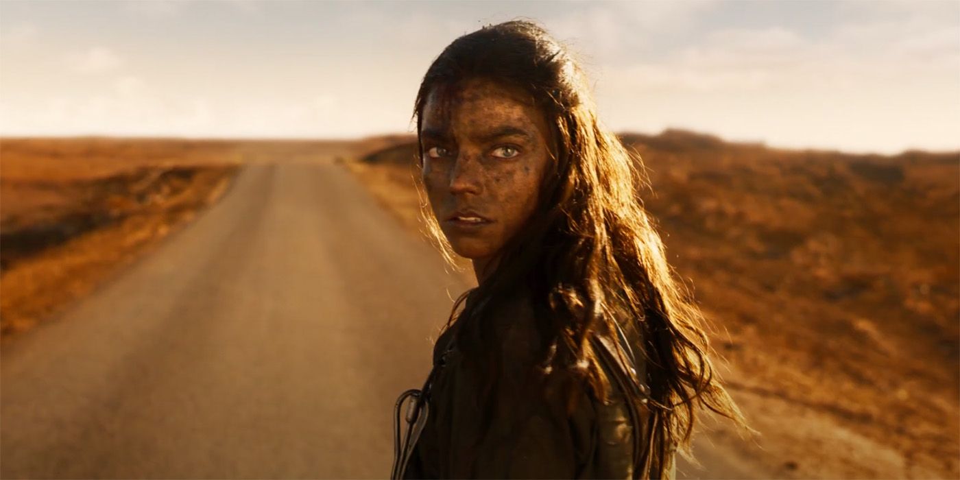 Anya Taylor-Joy as Imperator Furiosa covered in dirt and grease while standing on the open road in in Furiosa: A Mad Max Saga