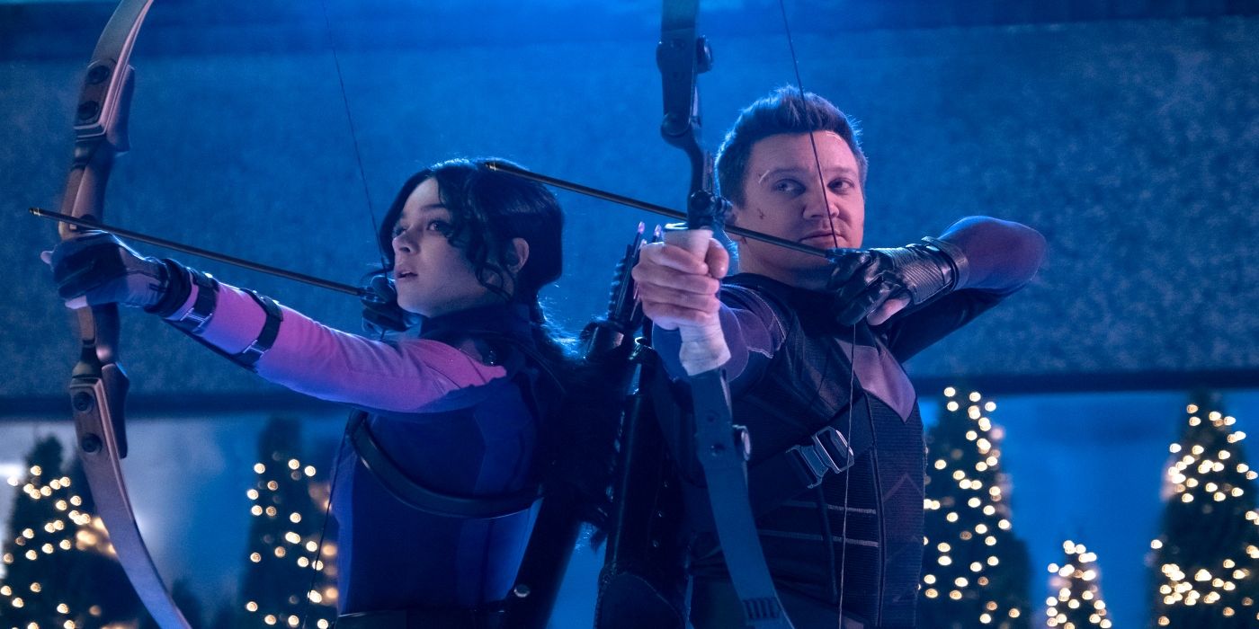 Hailee Steinfeld & Jeremy Renner hold bows & arrows with Christmas trees in the background in Hawkeye.