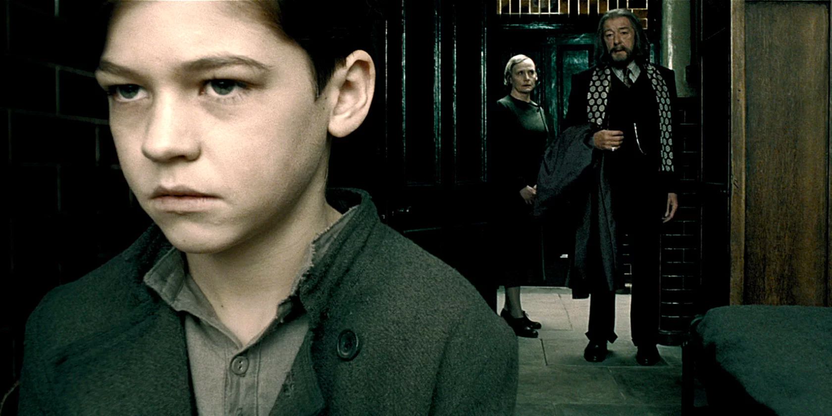 Tom Riddle (Hero Fiennes Tiffin) looks out his window while Dumbledore (Michael Gambon) visits him.
