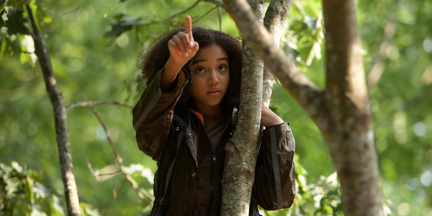 Actor Amandla Stenberg as Rue pointing to a tracker jacker nest in The Hunger Games